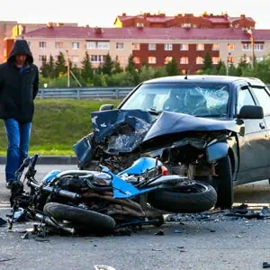 Man next to wrecked motorcycle and car post-accident - Mannis Law