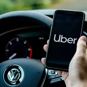 Man holding mobile with 'Uber' on screen in car - Mannis Law
